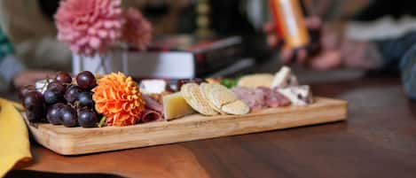 A wooden board with various cheeses, crackers, and grapes.