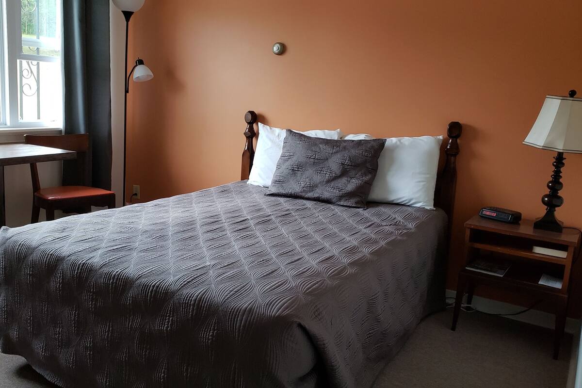 A bedroom with a bed, a nightstand, a table, and a chair.