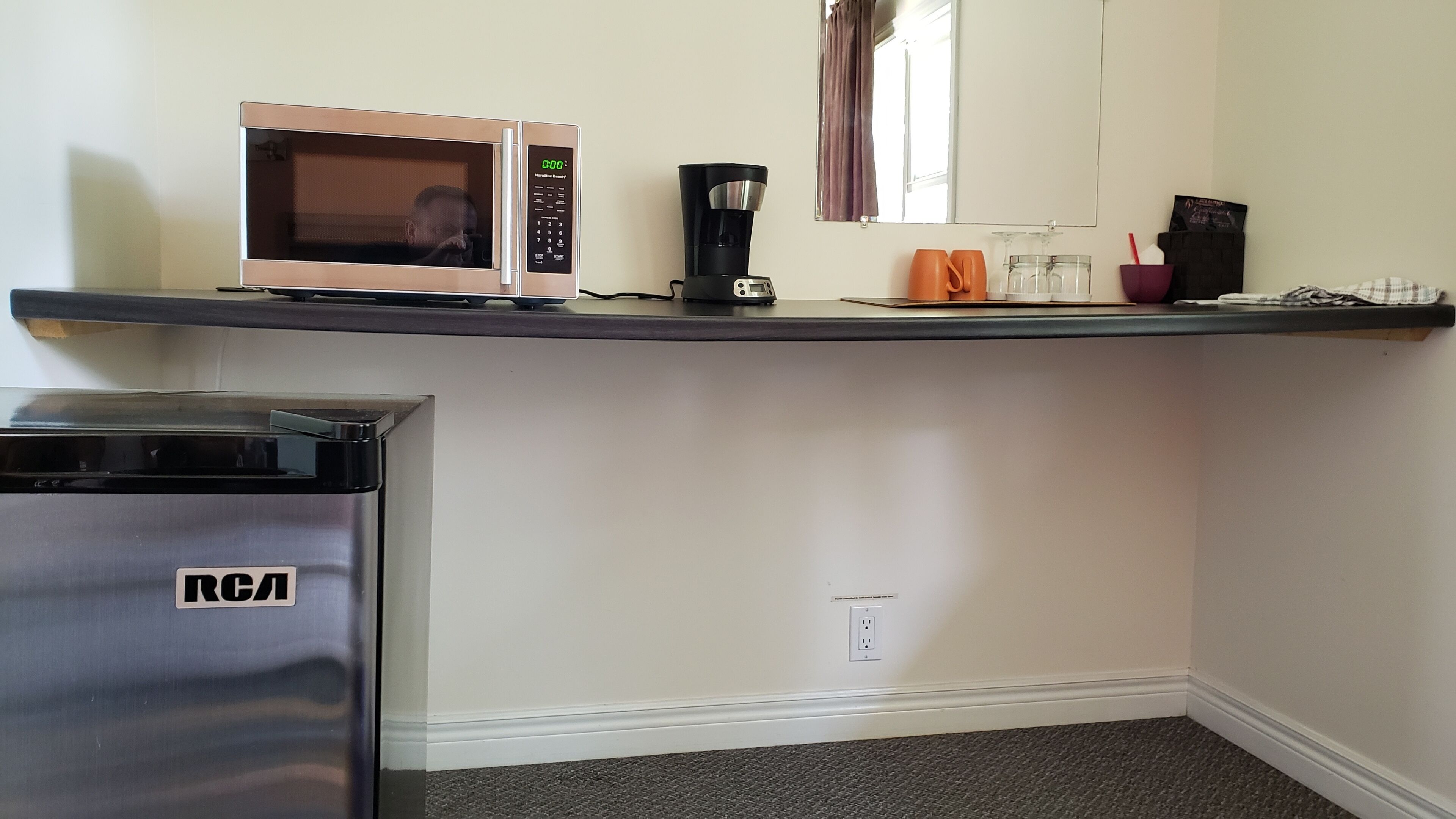 A kitchenette with a microwave, coffee maker, and a refrigerator.