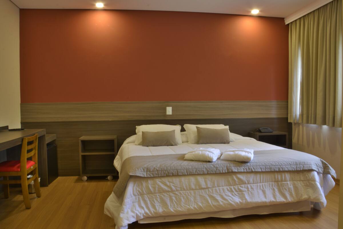 Un dormitorio con una cama grande, un escritorio y una silla.