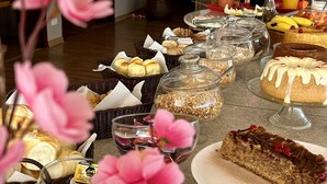 Una mesa de buffet con diversos alimentos, entre ellos pasteles, bollería y una variedad de bebidas.