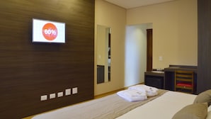 Una habitación de hotel con cama, escritorio, silla y espejo.
