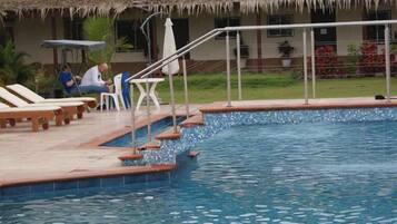Relax by the pool surrounded by lush greenery and comfortable lounge chairs.
