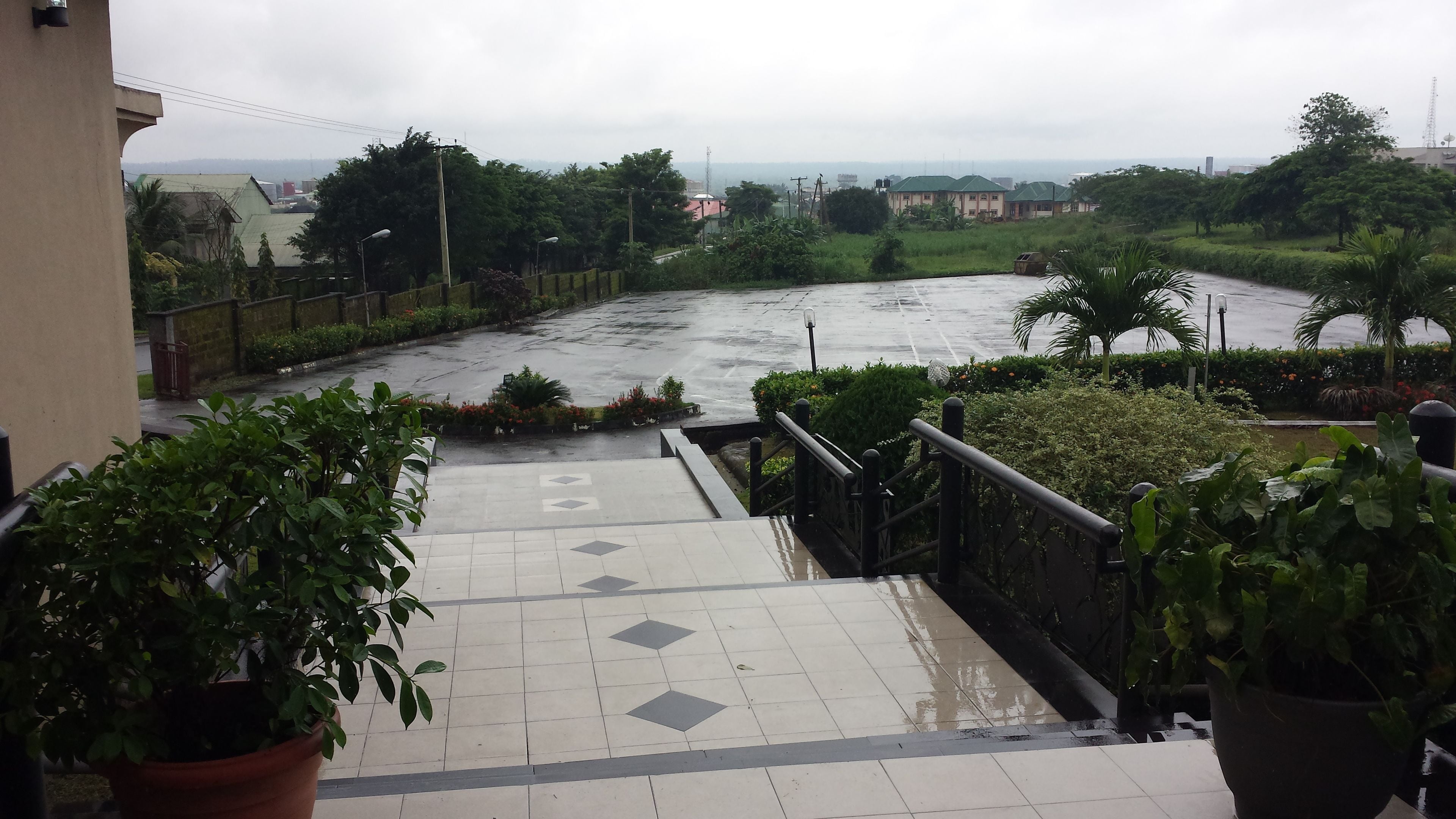 A wet staircase leading down to a river with greenery and buildings in the background.