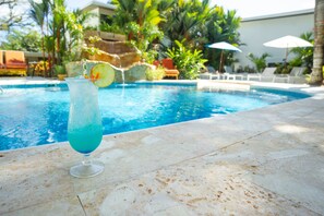 On voit clairement une piscine, avec un verre posé à proximité, entourée de chaises longues et de parasols.