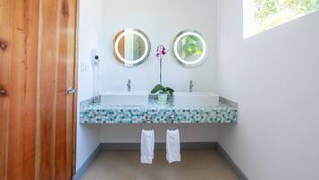 Un baño con dos lavamanos, una puerta de madera y un espejo con luz.