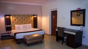A hotel room with a large bed, a desk, a chair, and a small table. - Eastgate Hotel Lekki (Lekki)