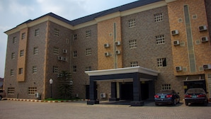 A multi-story building with a brick facade, air conditioning units, and a covered entrance. - Eastgate Hotel Lekki (Lekki)
