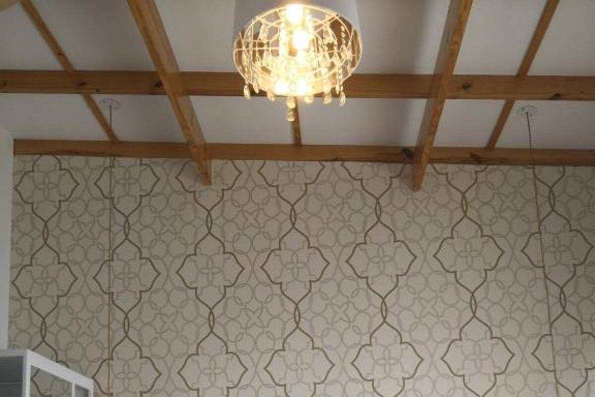 Un dormitorio con cama blanca, techo de madera y papel tapiz estampado.