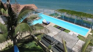 Una piscina con vistas al mar, rodeada de palmeras y una terraza de madera.