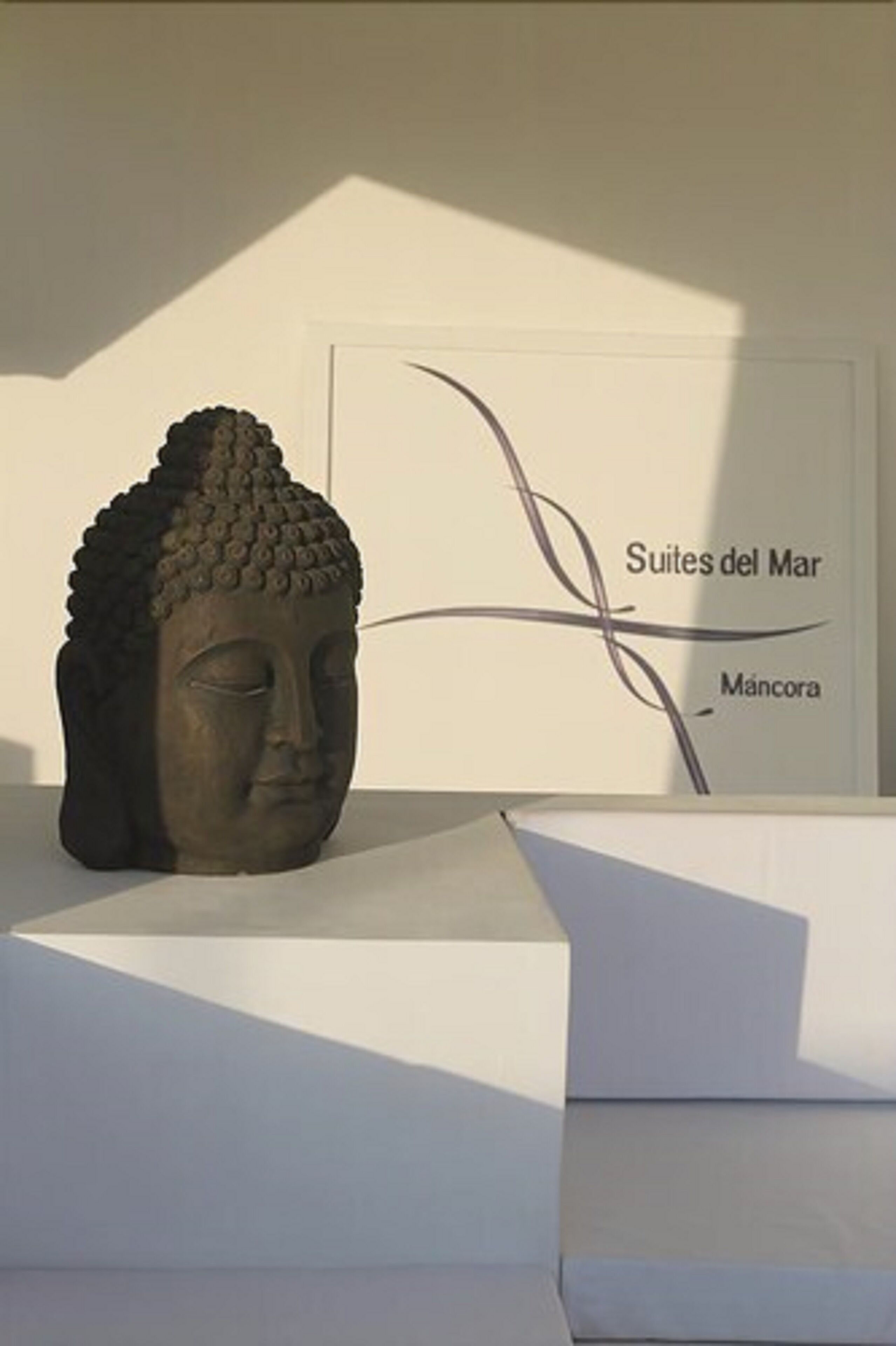 A Buddha statue on a pedestal with a wall sign in the background.
