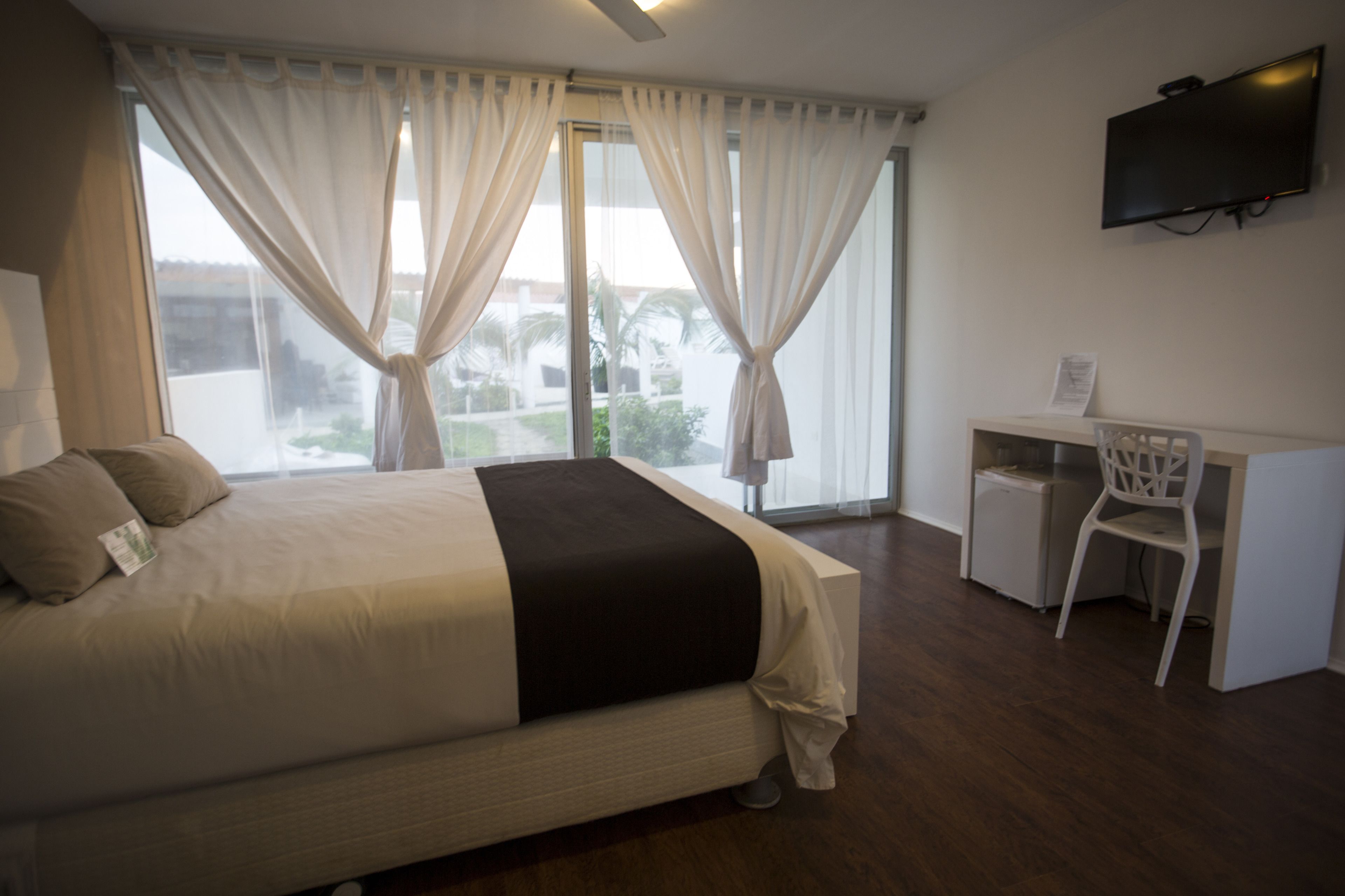 A hotel room with a bed, a desk, and a TV.
