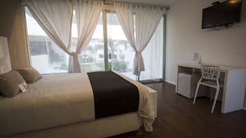 A hotel room with a bed, a desk, and a TV.