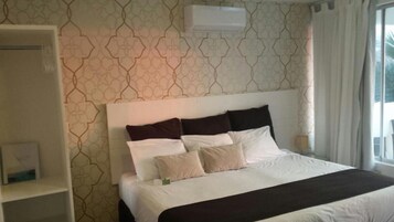 A hotel room with a bed, a nightstand, and a window with curtains.