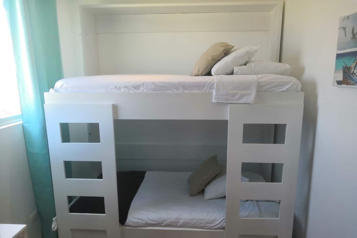 Una cama litera con estructura blanca y una cama inferior con colchón negro.