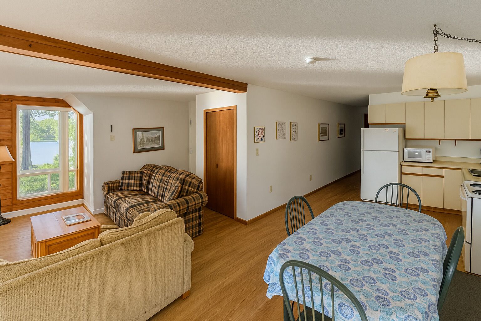 Een knus woongedeelte met een bank, een eettafel, een kitchenette en een groot raam met uitzicht op de omgeving.