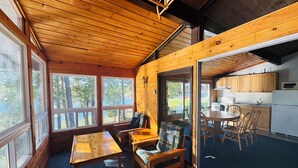 L’intérieur d’une cabane en bois comprend un coin repas, une cuisine et de grandes fenêtres.