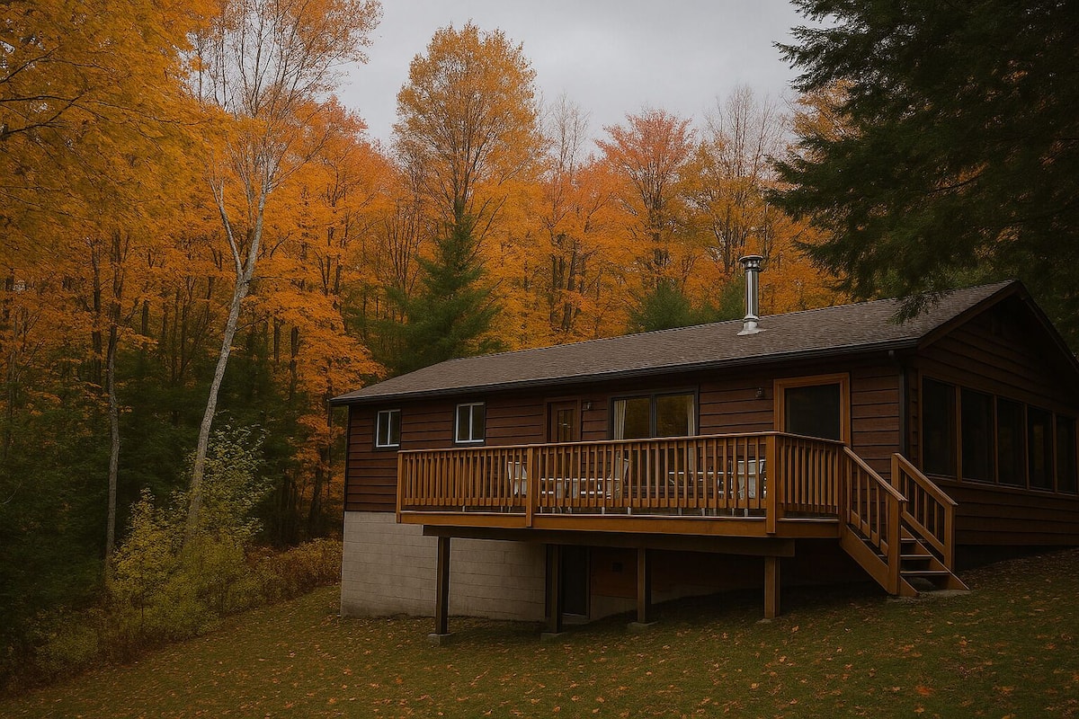 A cabin with a wooden deck and a staircase leading to the entrance.