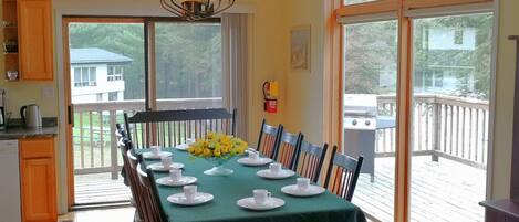 A dining area with a table set for a meal, chairs, a chandelier, and a view of the outdoors.