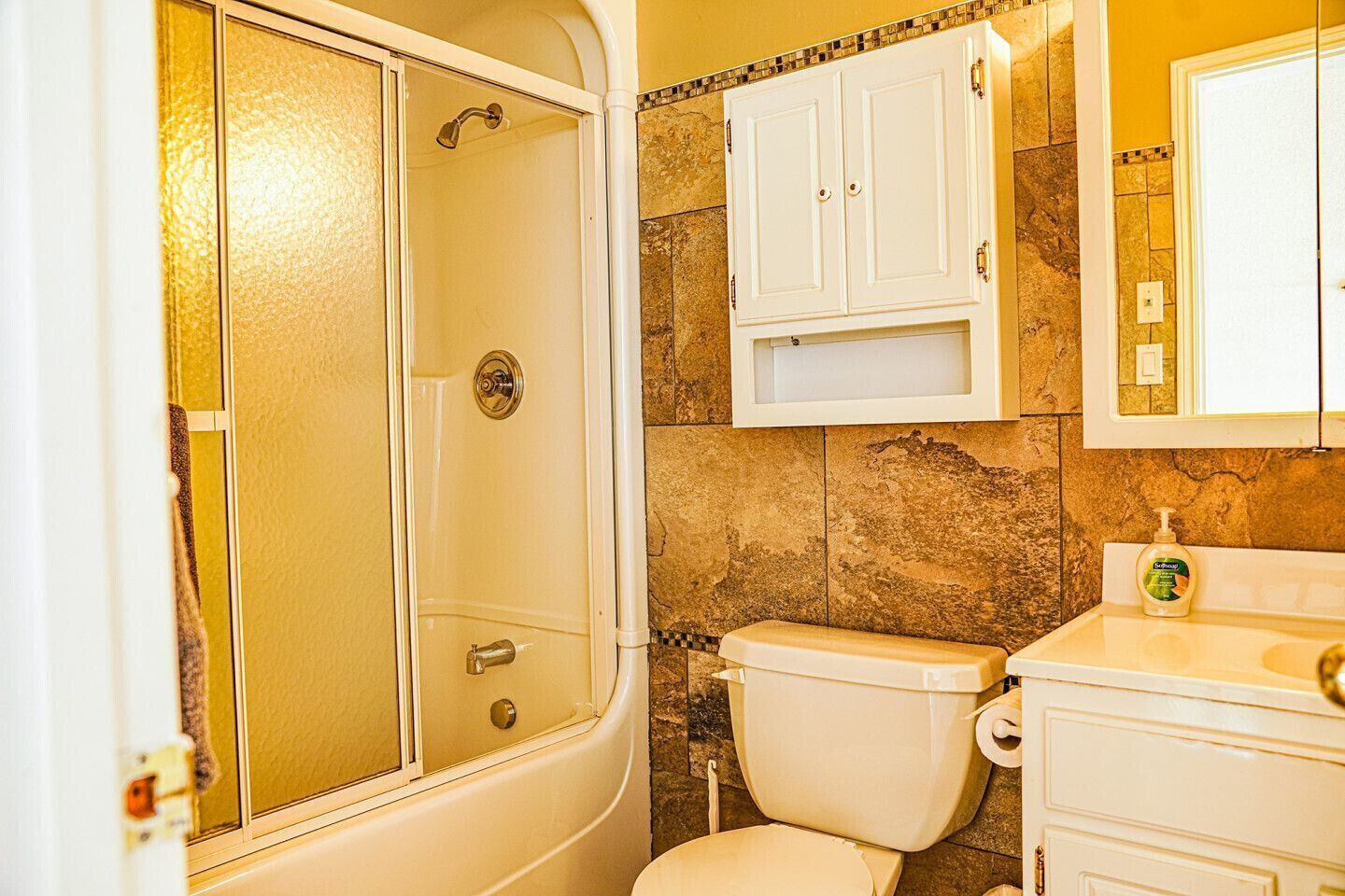 A bathroom with a shower, toilet, and a sink with a mirror above it.
