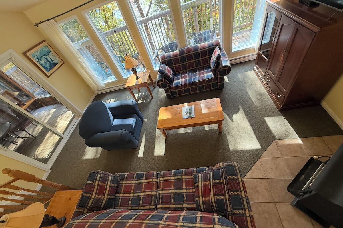 A cozy living room with a plaid sofa, a blue armchair, and a wooden coffee table.