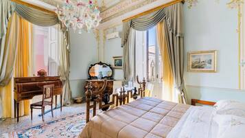 Una habitación con cama, escritorio, silla, cómoda y araña.