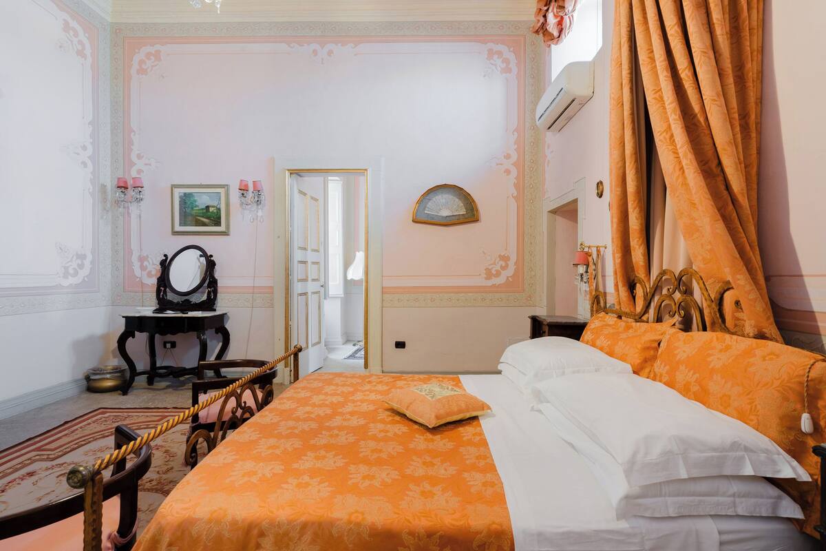 Un dormitorio con una cama grande, un aparador, un espejo y una puerta que da a otra habitación.