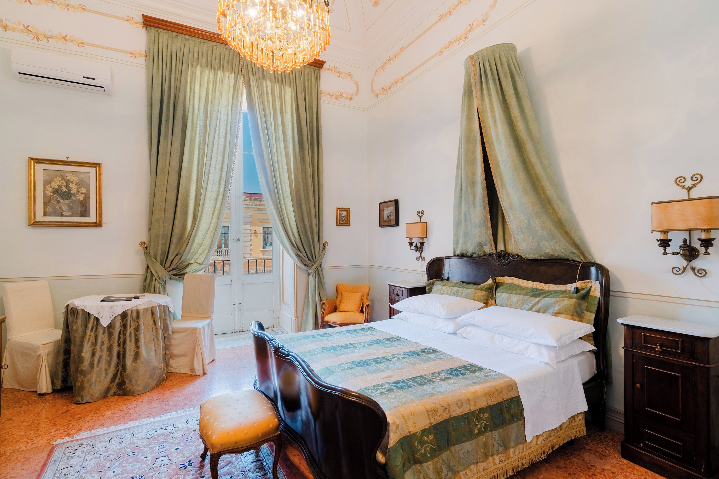 A bedroom with a bed, a chair, a table, and a lamp.