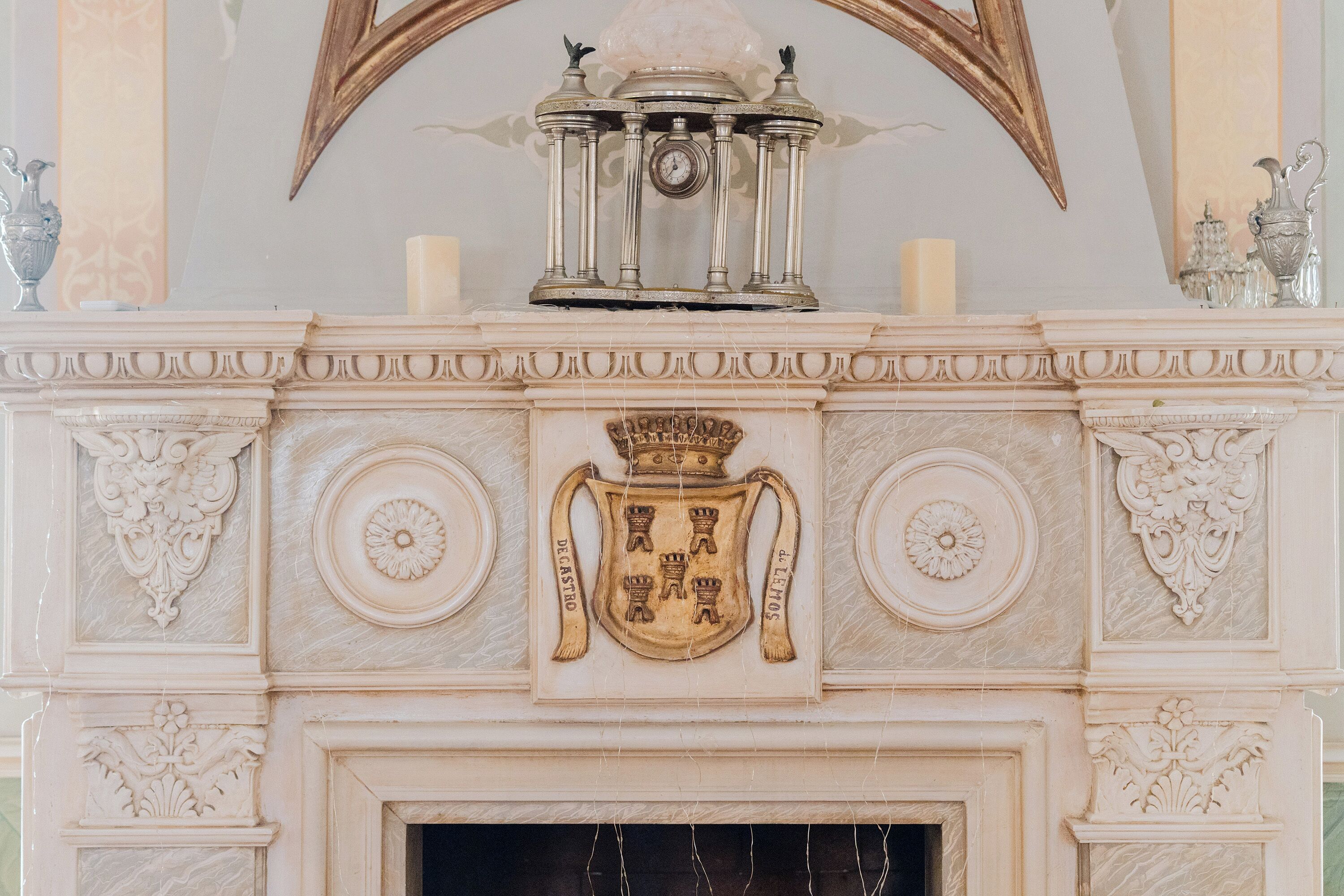 A detailed fireplace with a coat of arms and a clock above it.