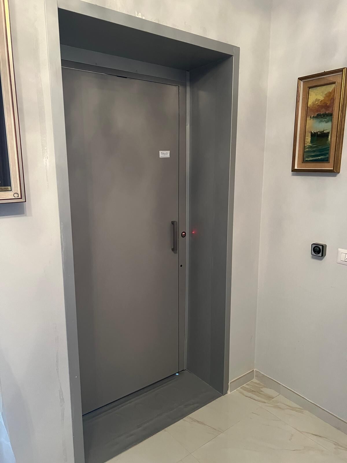 A closed elevator door with a small sign on the wall above it.