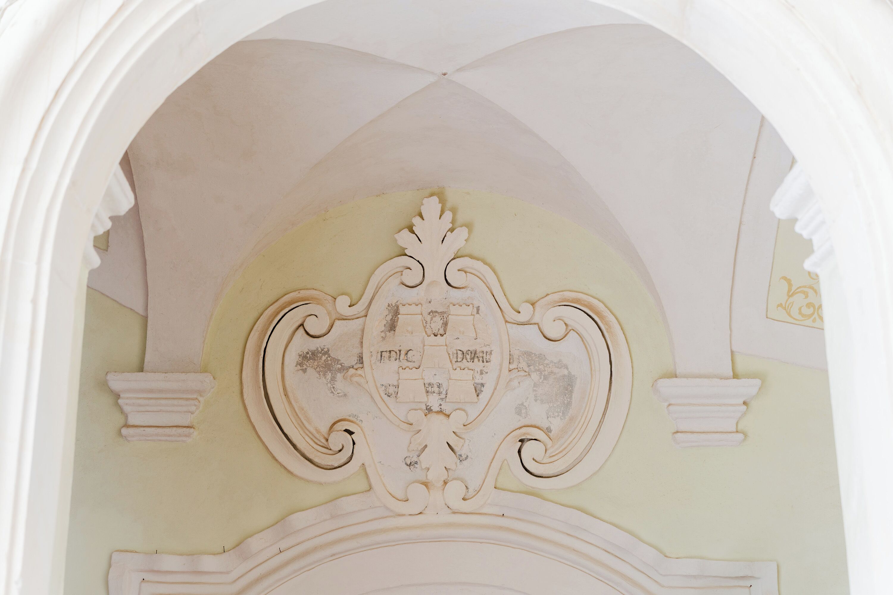 Un techo ornamentado con un emblema central y molduras decorativas.