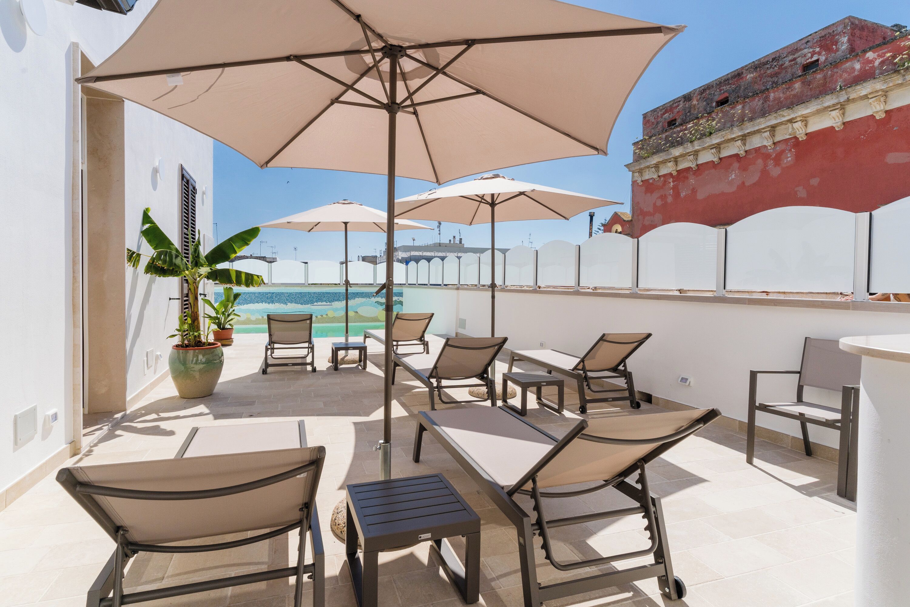 A rooftop terrace with outdoor seating, umbrellas, and a view of the sea.