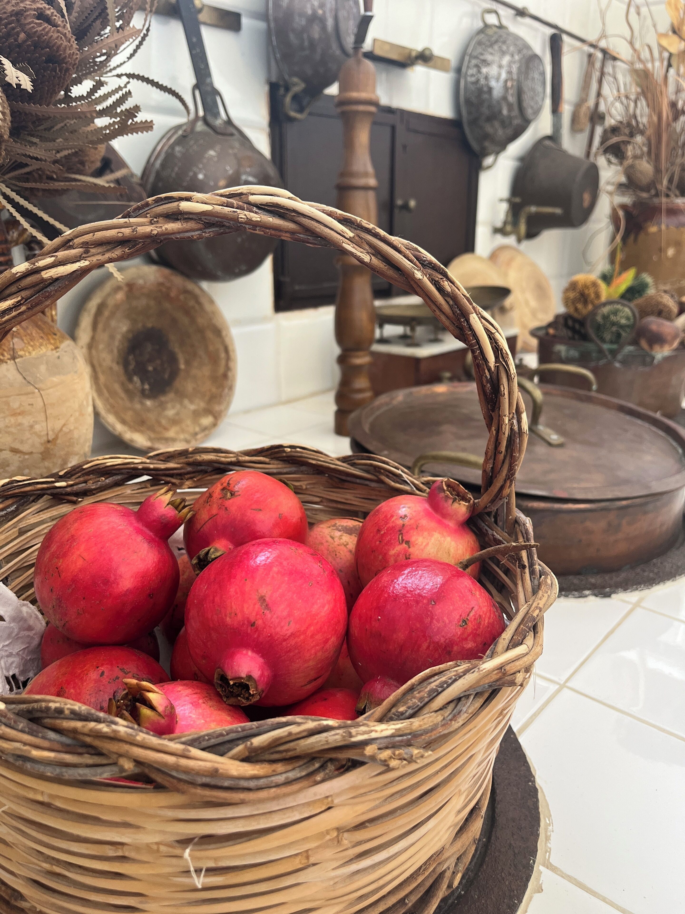 A wicker basket filled with pomegranates on a tiled floor.