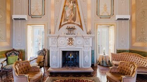 Una sala imponente con chimenea, sillones ornamentados y una araña.