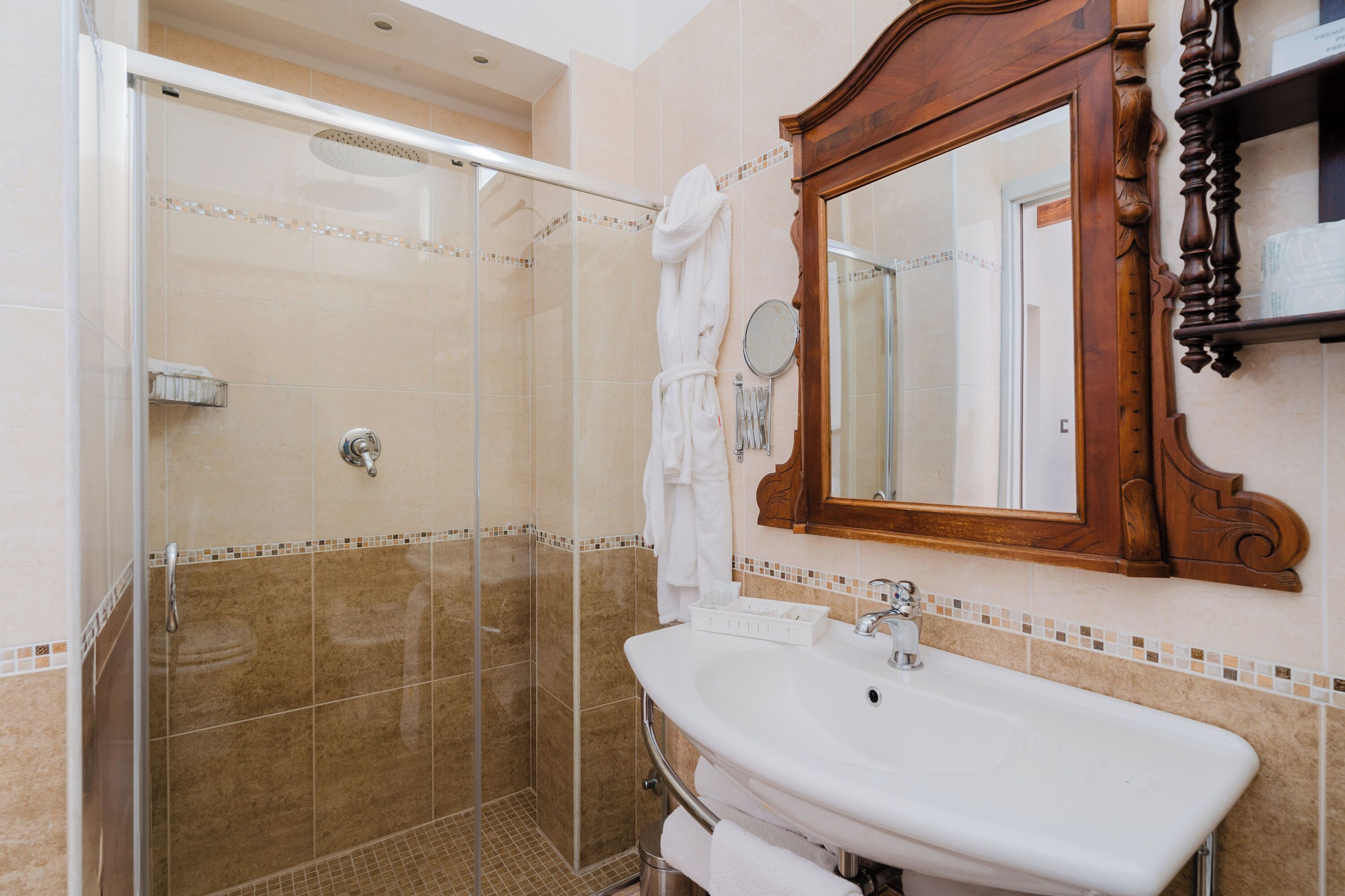 A bathroom with a glass-enclosed shower, a white sink, and a wooden-framed mirror.