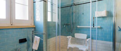 Un baño con ducha envuelta en vidrio, un lavamanos blanco y un perchero para toallas.