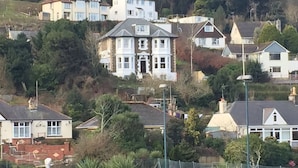 A residential area with various houses, including a prominent white house with a large front porch and a gabled roof. - Cairn House (Ilfracombe)