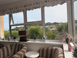 Una habitación con un ventanal grande, sillas tapizadas a rayas, una pequeña mesa redonda y un valance decorativo en la ventana.