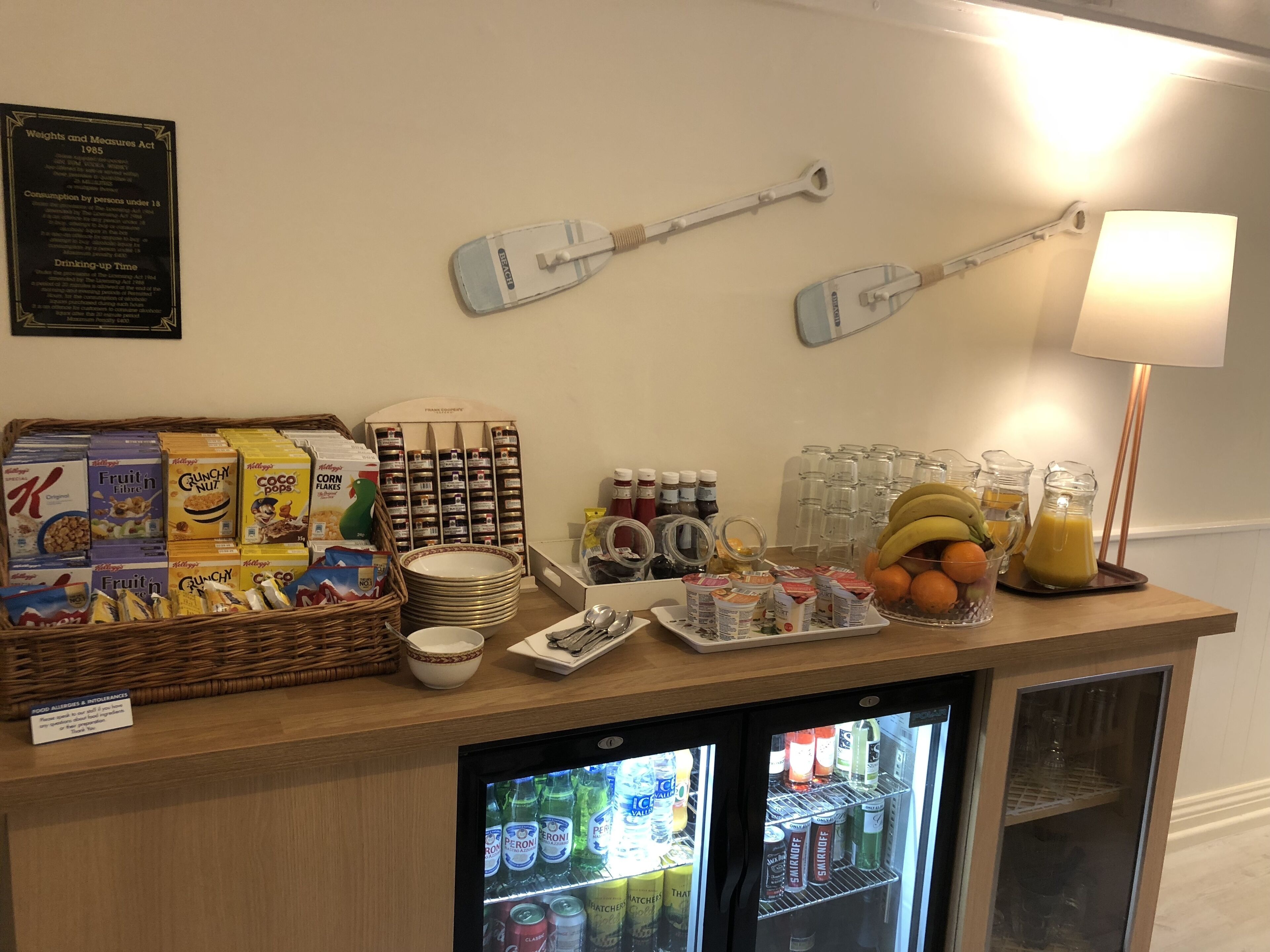 Een ontbijtbuffet met cornflakes, fruit, drankjes en een koelkast vol met verfrissingen.