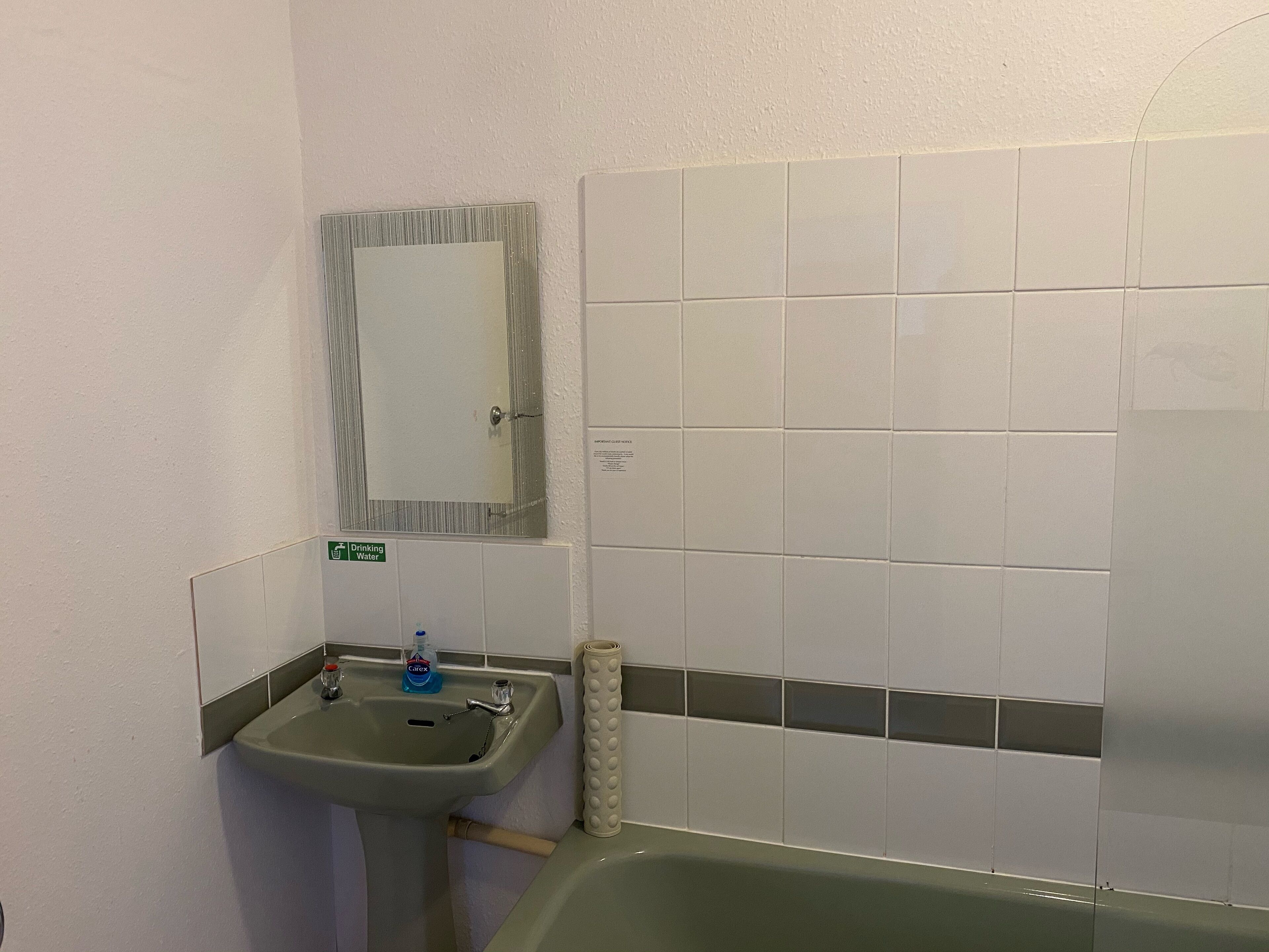 A bathroom with a sink, mirror, and tiled walls.