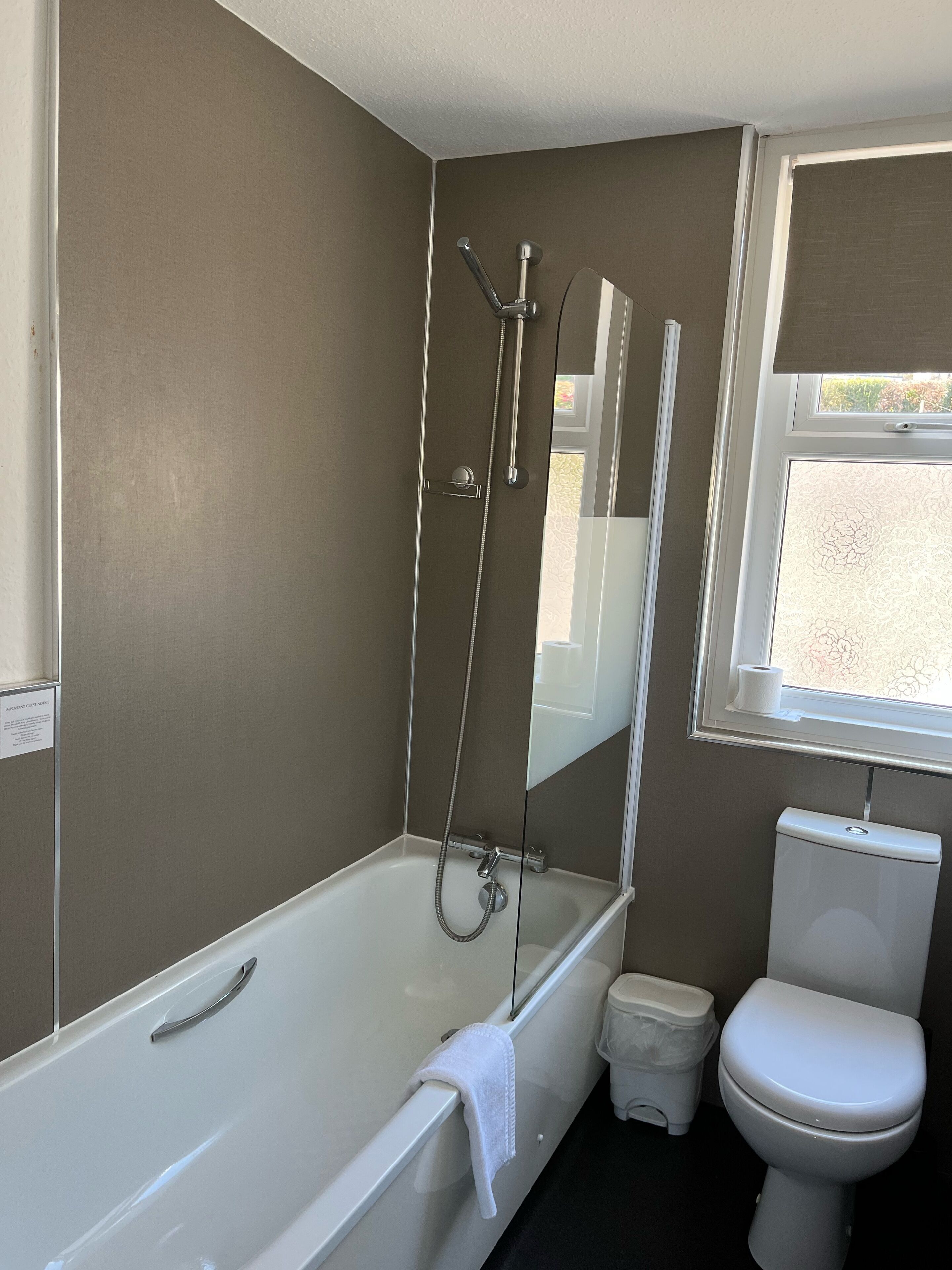 Et badeværelse med badekar, toilet og et vindue.
