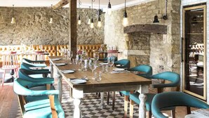 A restaurant with a long wooden table set for dining, surrounded by teal upholstered chairs. - Old Stocks Inn (Cheltenham)