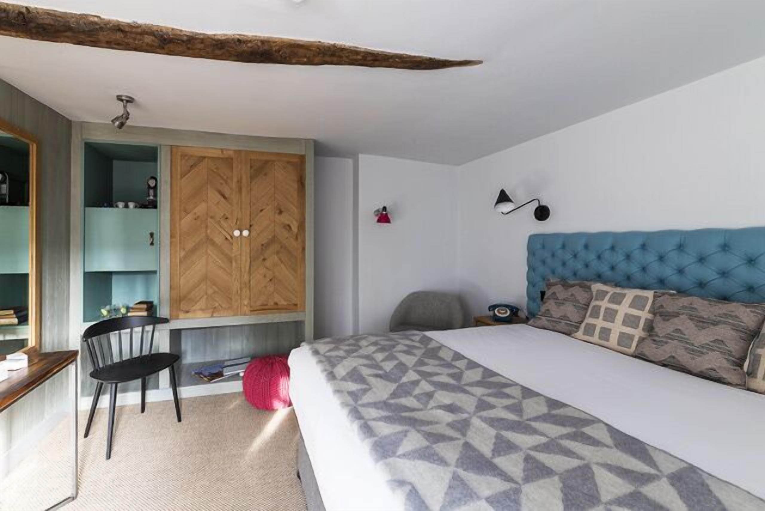 Ein Schlafzimmer mit Bett, Schreibtisch, Stuhl, Kleiderschrank und einem blauen Kopfteil.