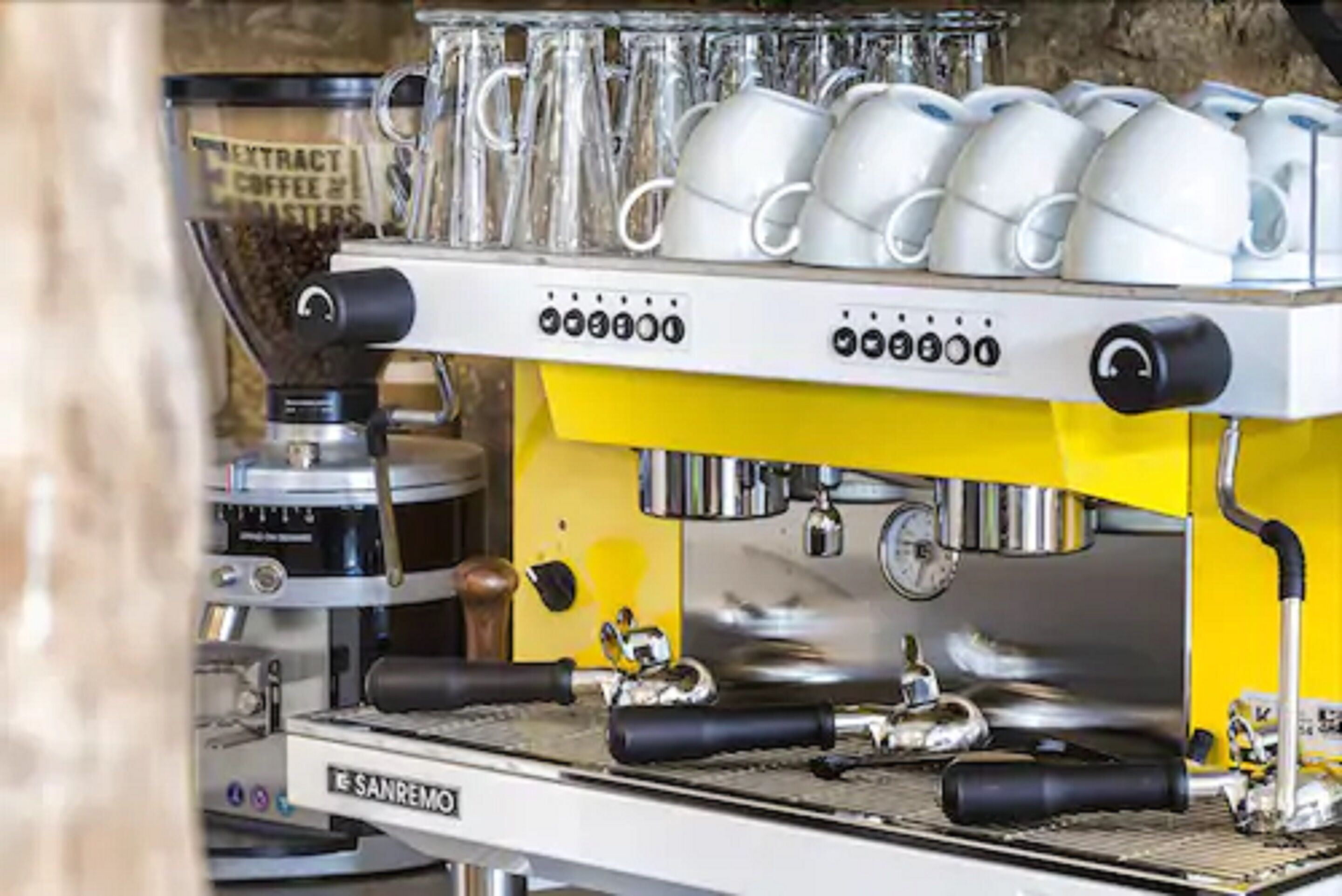 A coffee machine with multiple coffee cups and a coffee grinder.