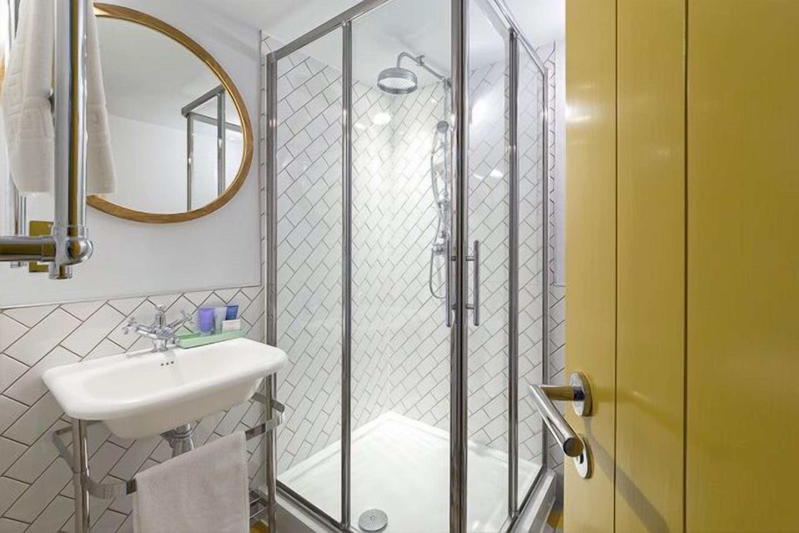 A modern bathroom with a glass-enclosed shower, a white sink, and a mirror.