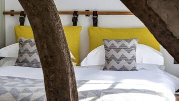 A bed with white bedding and two pillows, one with a zigzag pattern and the other plain.
