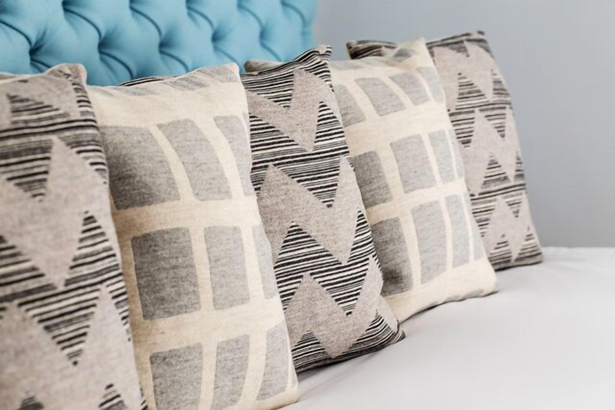 Cuatro almohadas con diseños geométricos sobre una cama.