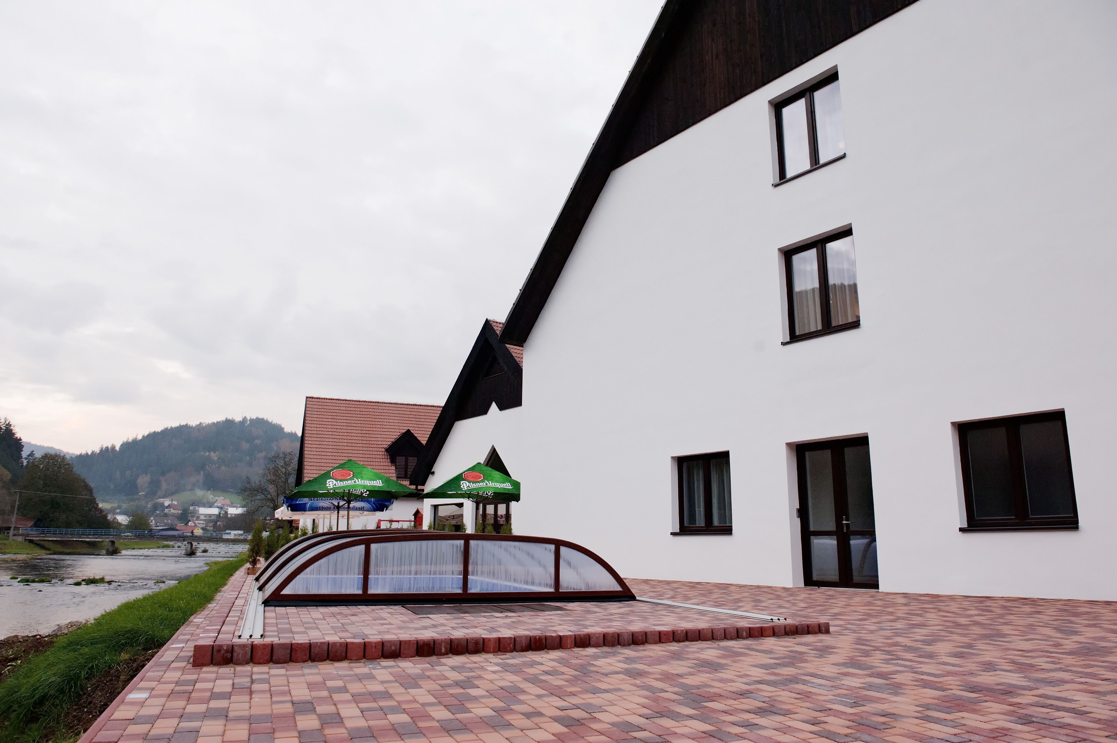 A modern building with a sloped roof, a paved walkway, and a small bridge.