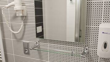 Un baño con un lavabo blanco, un espejo y un secamanos.