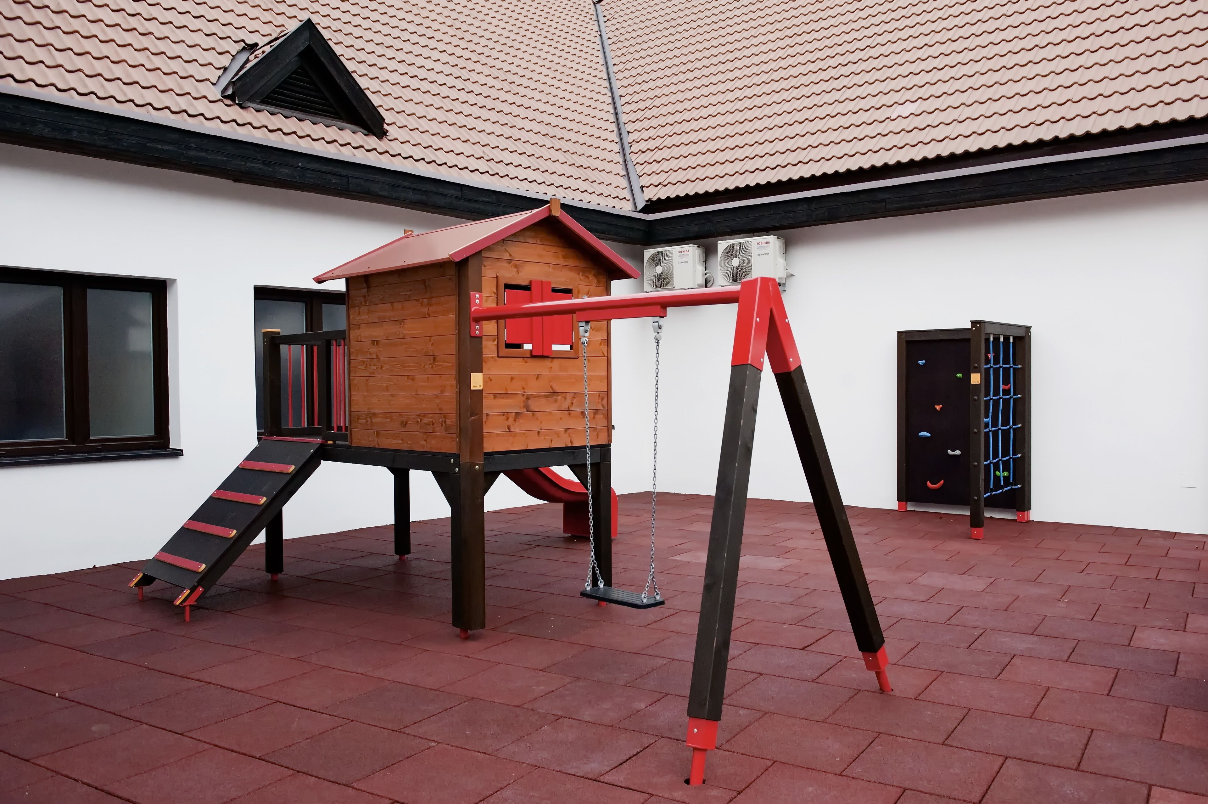 Un parque infantil con una casita de madera, un tobogán y columpios.